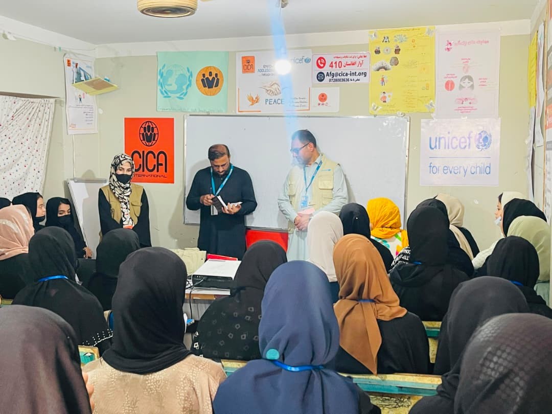 Visitors and facilitators speaking with women trainees